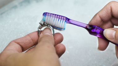 Cleaning a diamond ring with soapy water and a toothbrush.