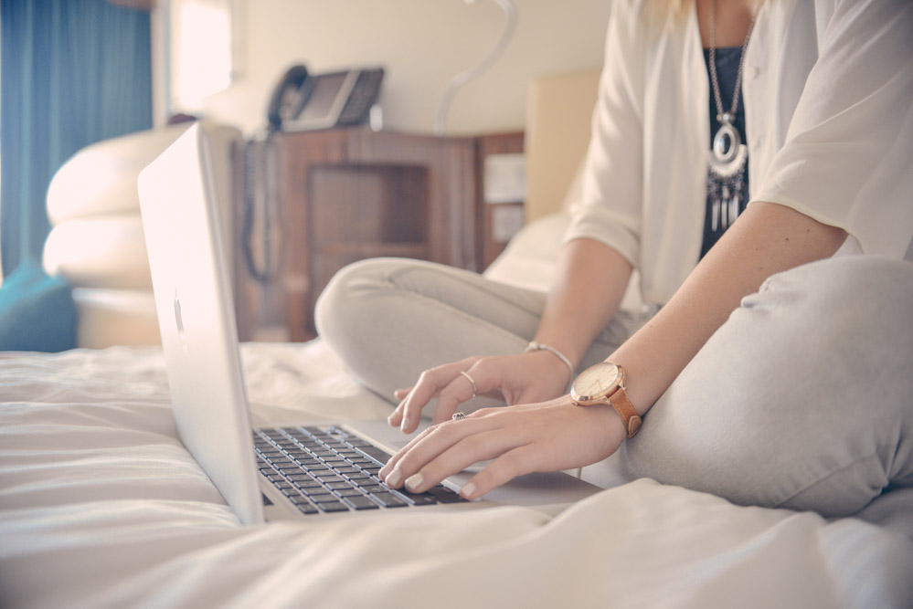 Casual-Business-Woman-Typing-On-Laptop-Whilst-In-Bed