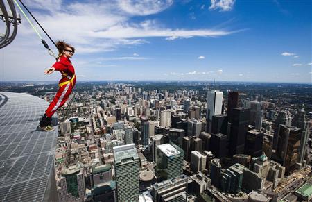 A reporter leans over the edge of the catwalk during the media preview for the "EdgeWalk" on the CN Tower in Toronto, July 27, 2011. REUTERS/Mark Blinch