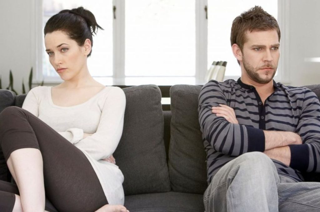 Pareja distante en el sofá como señales de terminar un noviazgo