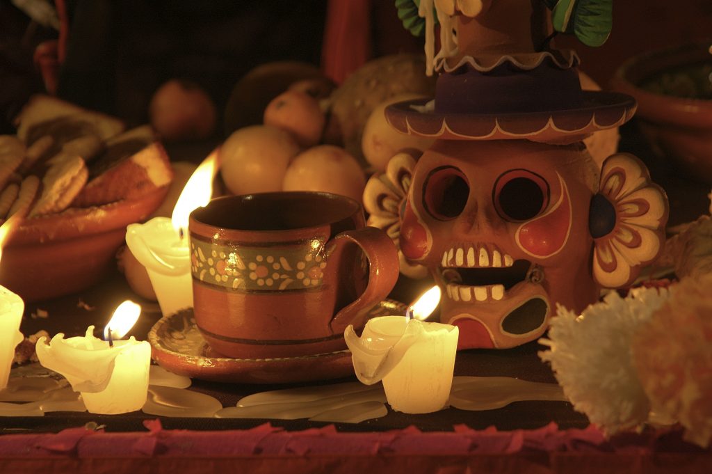 Taza con veladora encendida como parte de un altar de Día de Muertos