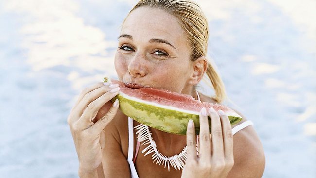 244315-woman-sitting-on-beach-eating-watermelon
