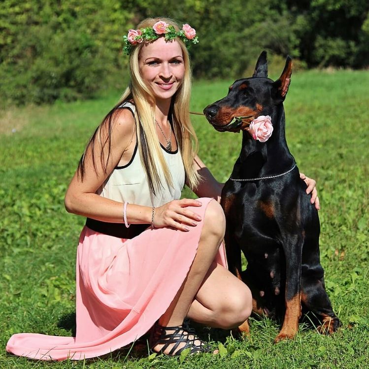 doberman y mujer de rosa