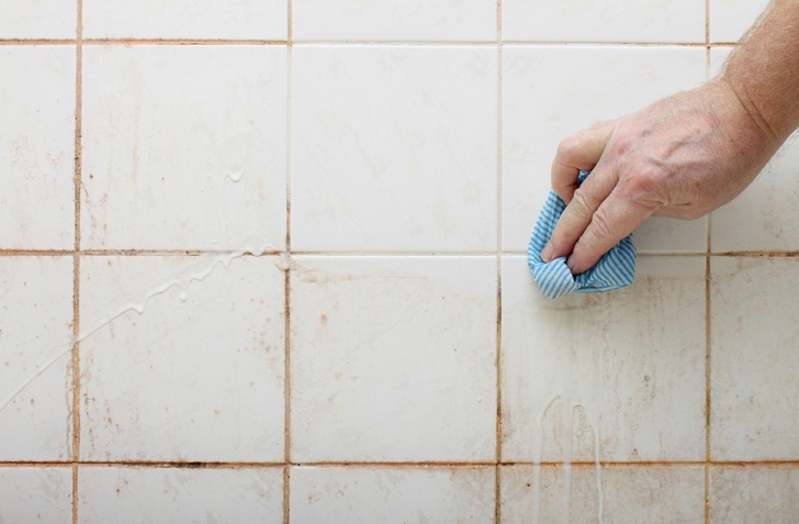 cleaning dirty shower and  bathroom tiles with mould