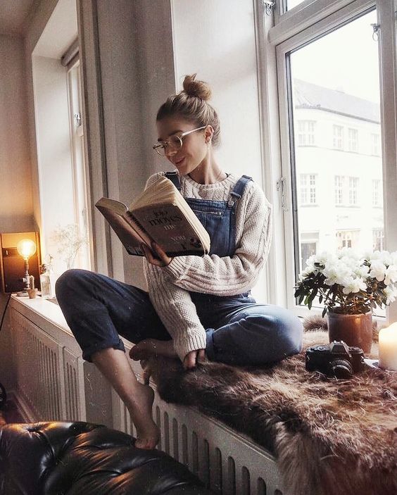 sentada leyendo libro junto a ventana