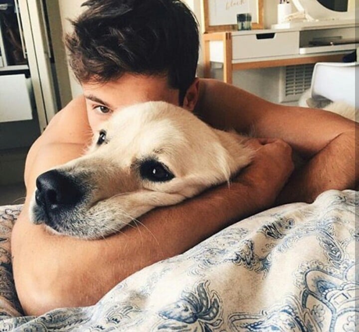chico abrazando perro en la cama