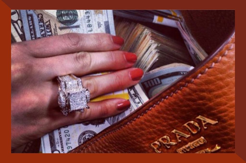 Mano con anillo de diamantes colocando dinero en una cartera de lujo, ideal para ilustrar retos ahorrar