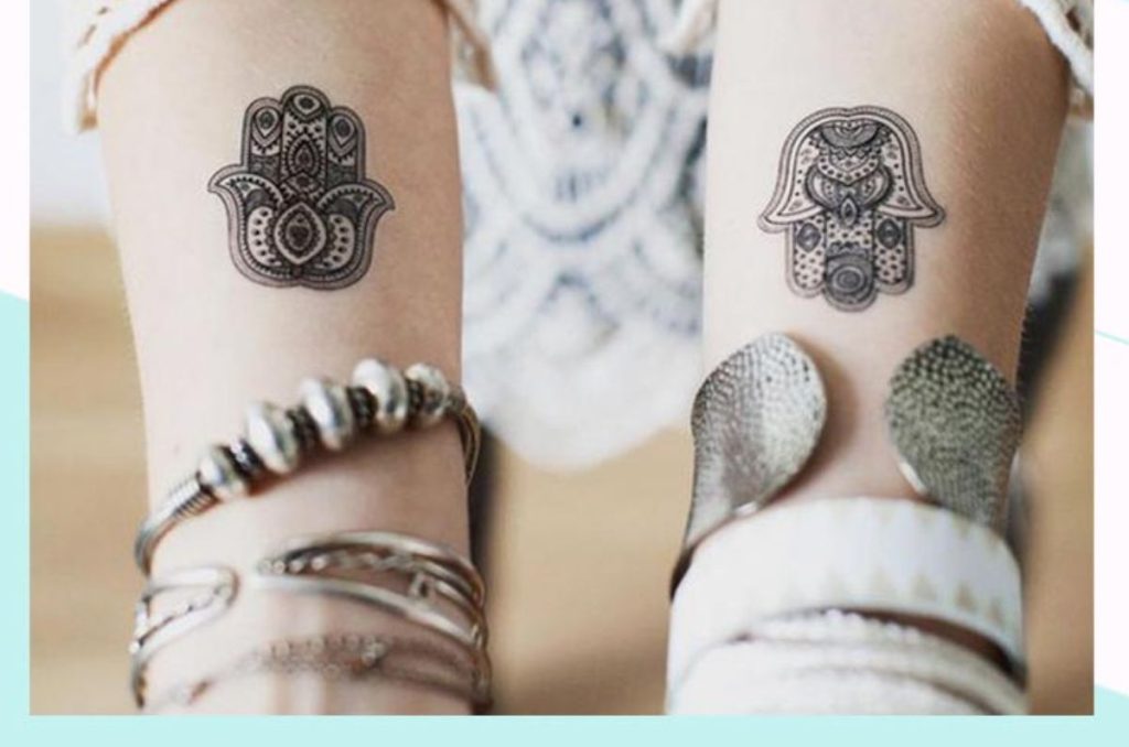 Tatuajes de Hamsa hand en los brazos con diseño espiritual y decorativo