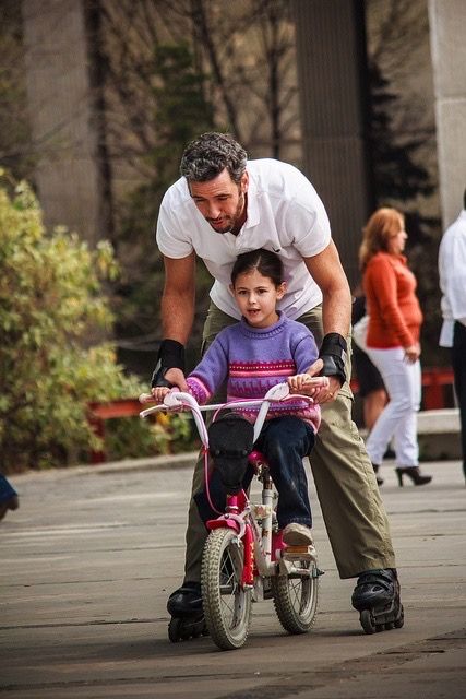 papá e hija intentando andar en bici 