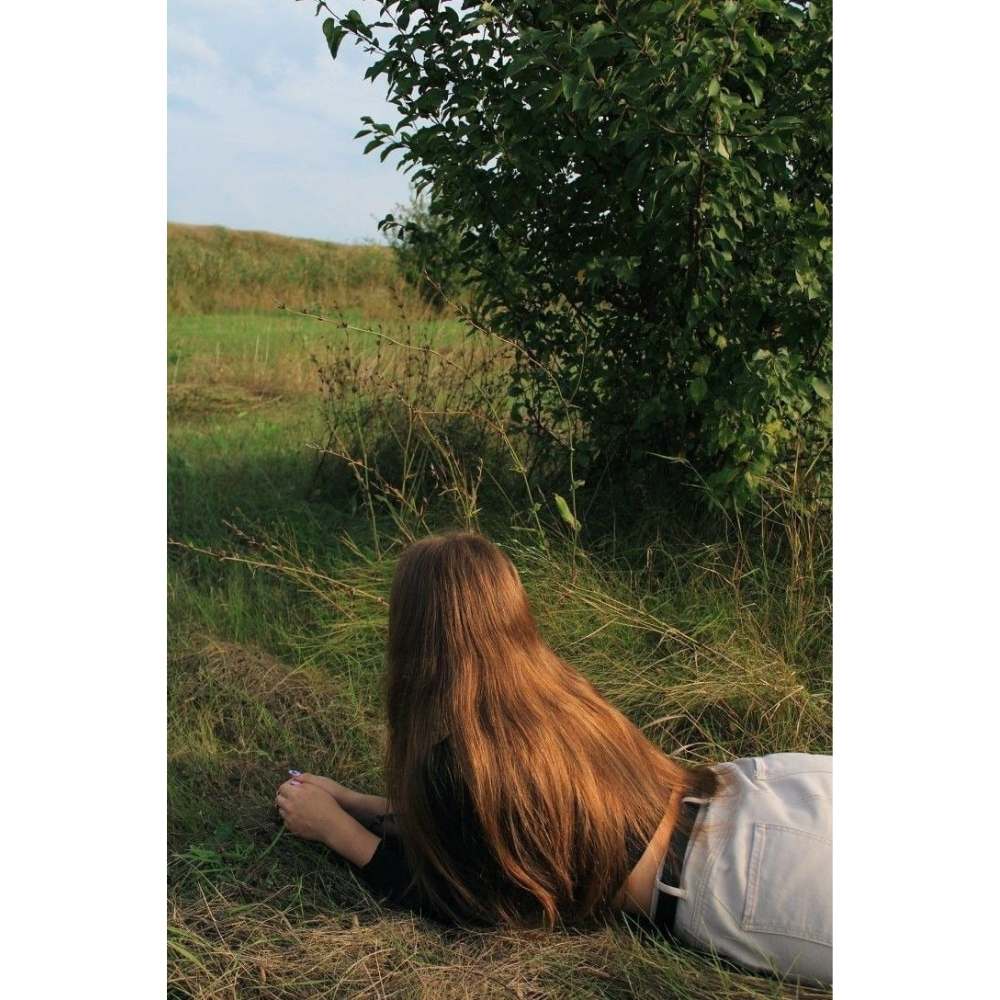 Chica con cabello largo recostada boca abajo sobre pasto como consecuencia d ela luna llena