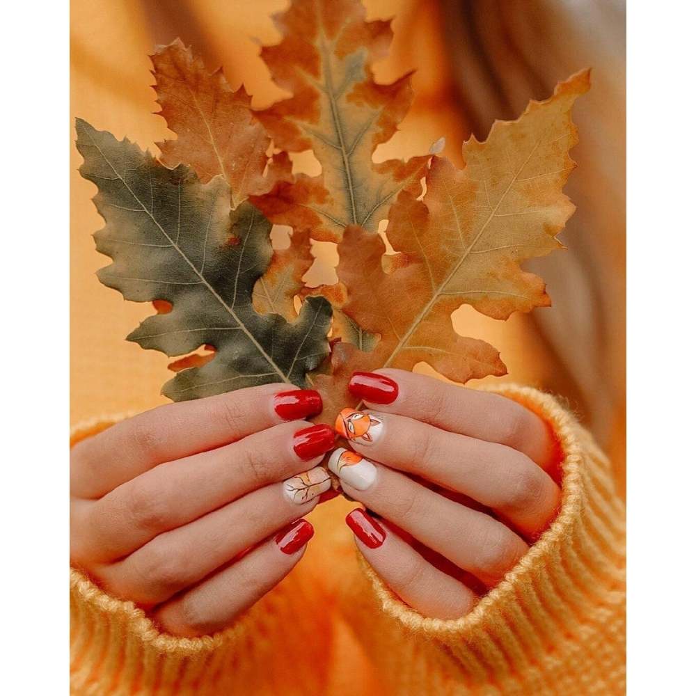 Chica sosteniendo unas hojas secas luciendo una manicura de otoño