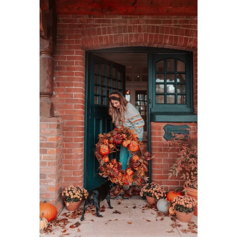 Chica con corona de hojas secas y calabazas para decorar su casa