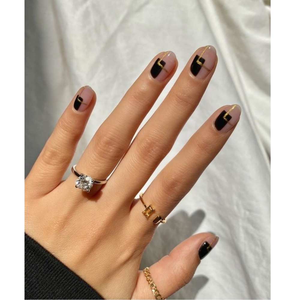 Uñas cortas en forma almendra con diseño minimalista en cuadros negro y dorado con relleno negro y contorno dorado