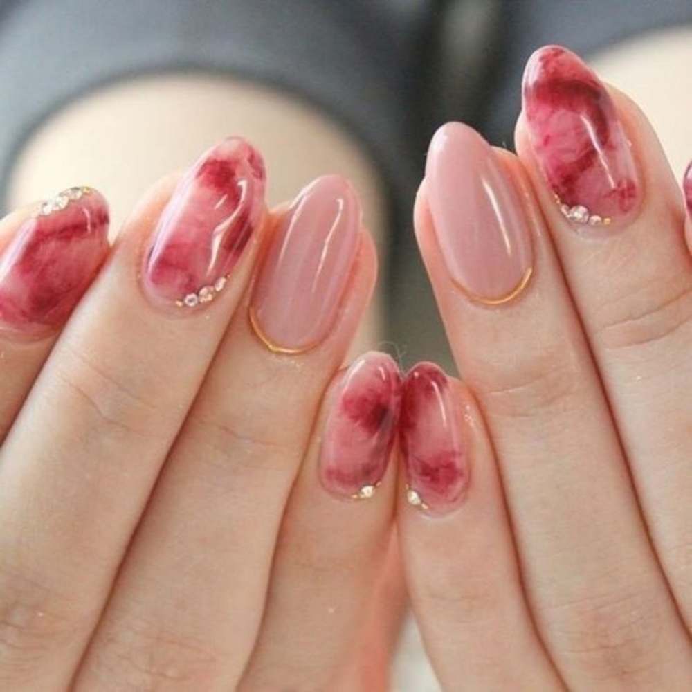 Uñas en forma almendra con efecto acuarela en color rojo sobre base nude