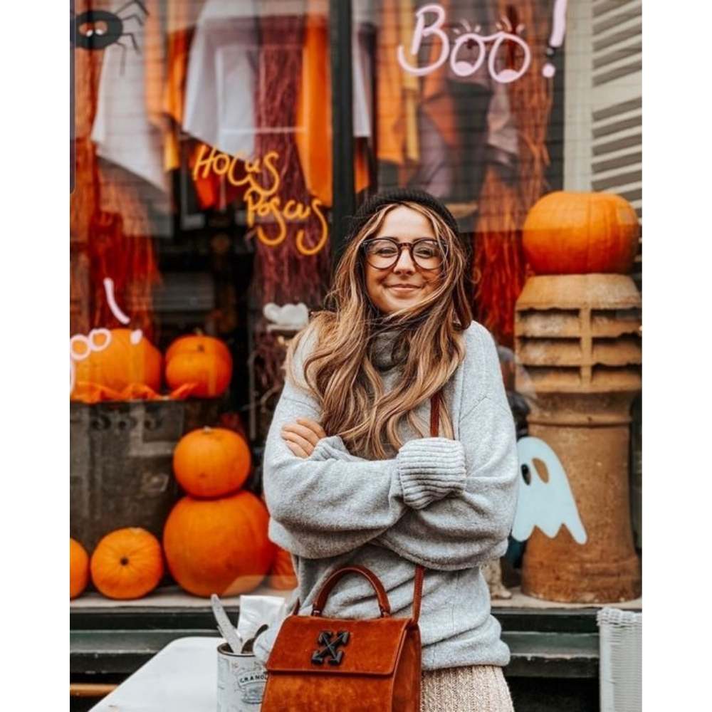 Aprovecha las decoraciones de las tiendas para lograr unas fotos cute Chica posando junto a escaparete de tienda de halloween