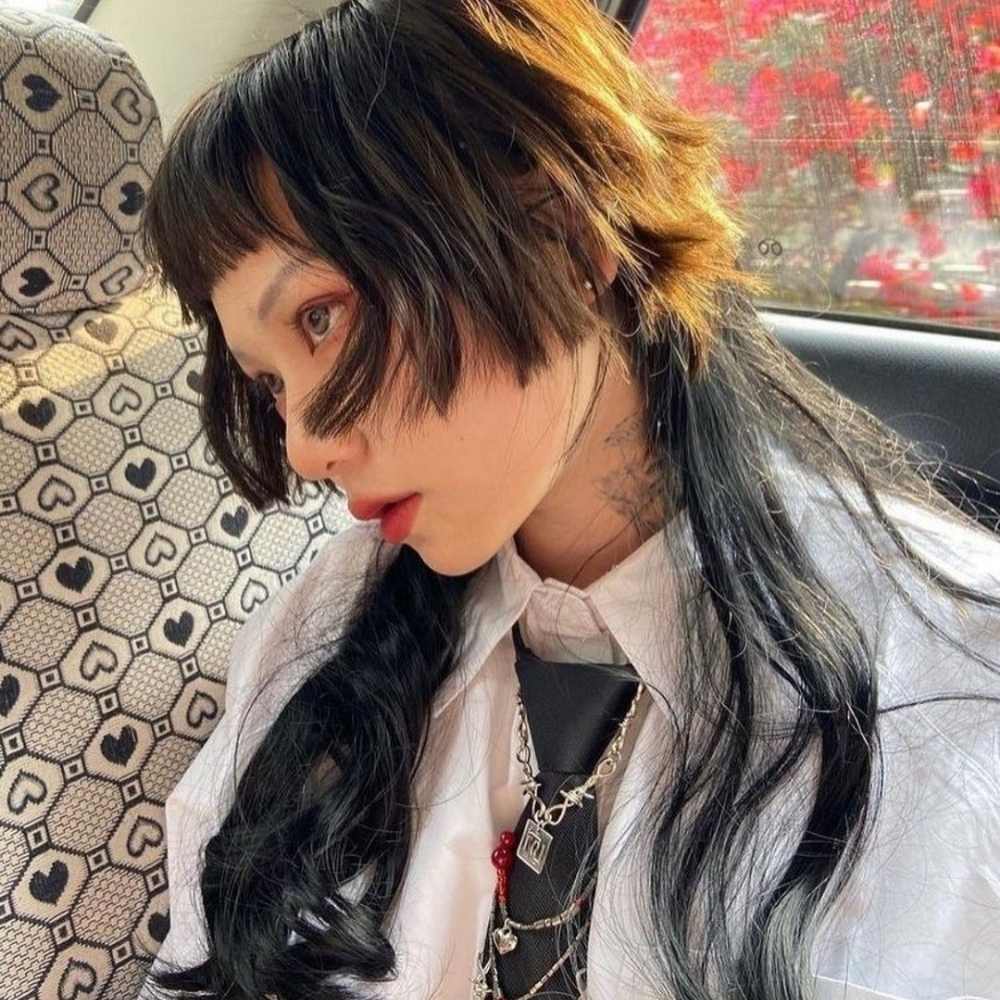 El jellyfish haircut se lleva en cabello negro en conjunto con un outfit de camisa blanca con corbata negra y cadenas como accesorios