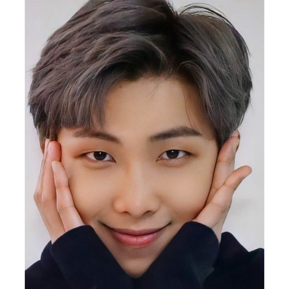 RM en close up tocando su rostro con ambas manos en una pse muy tierna