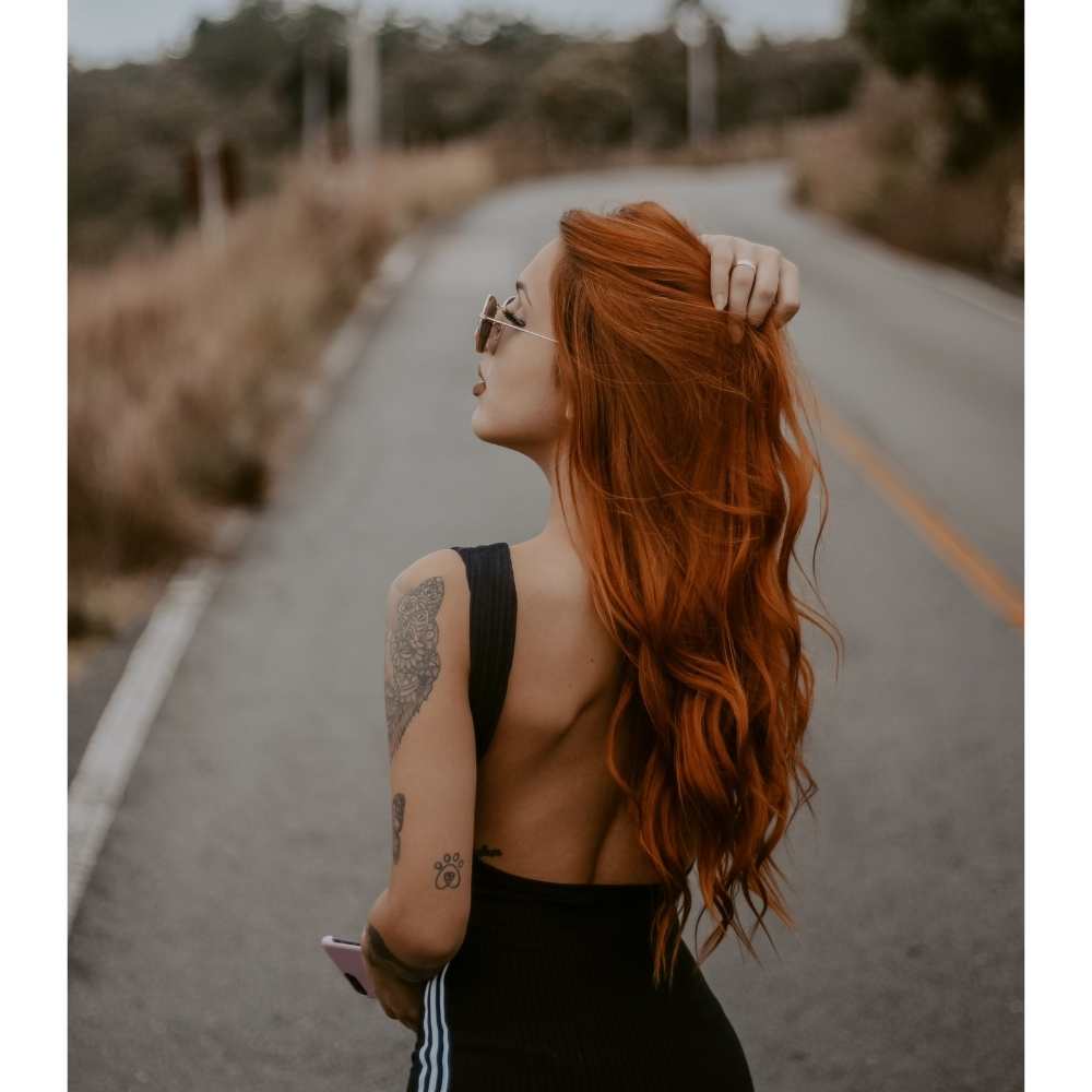 Chica con cabello cobrizo suelto largp y un vestido negro 