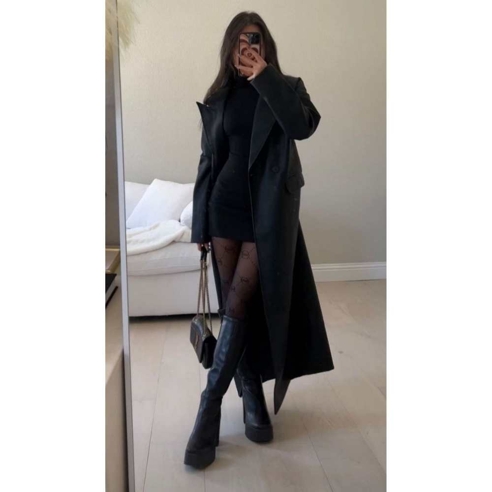 Look con botas largas con plataforma Outfit con gabardina larga negra, blusa cuello tortuga y minifalda pegada