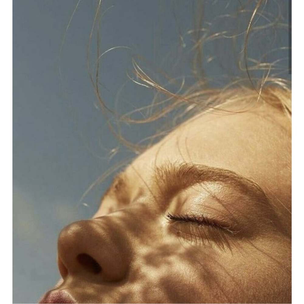Chica a la luz del sol con los ojos cerrados decretando como parte de los rituales para proteger tu energía