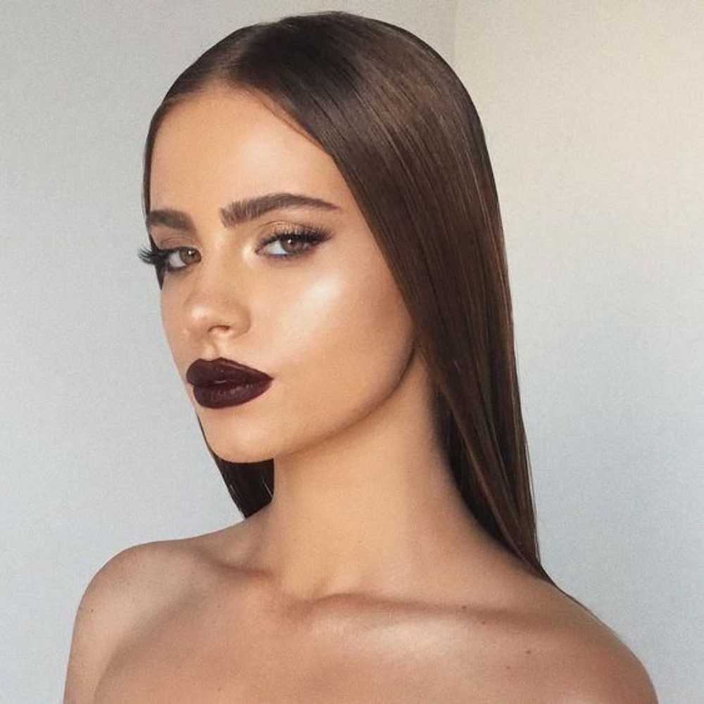 Modelo piel media bronceada con cabello castaño claro lacio y largo luciendo labios oscuros