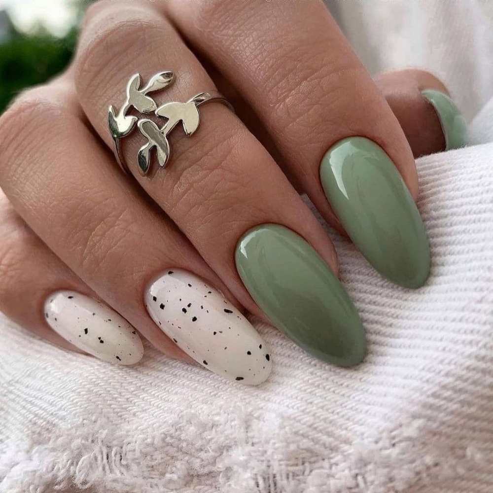 Uñas color verde olivo con diseño en blanco y efecto cascarón .