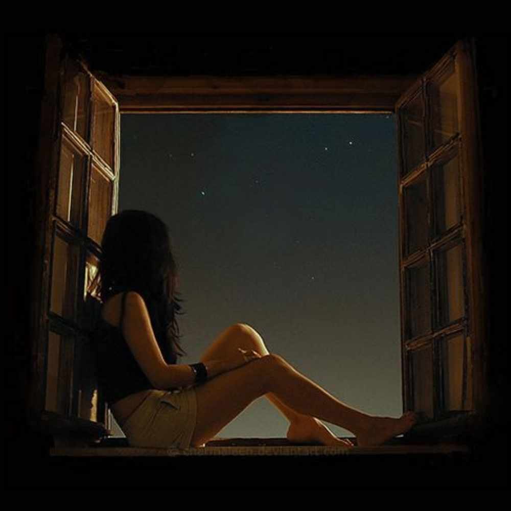 Chica sentada en una ventana observando la luna y el cielo nocturno