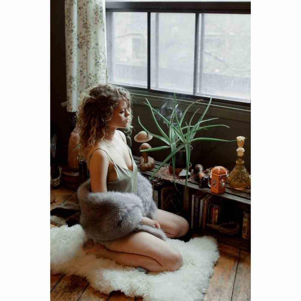 Chica sentada frente a ventana meditando y decretando en eclipse