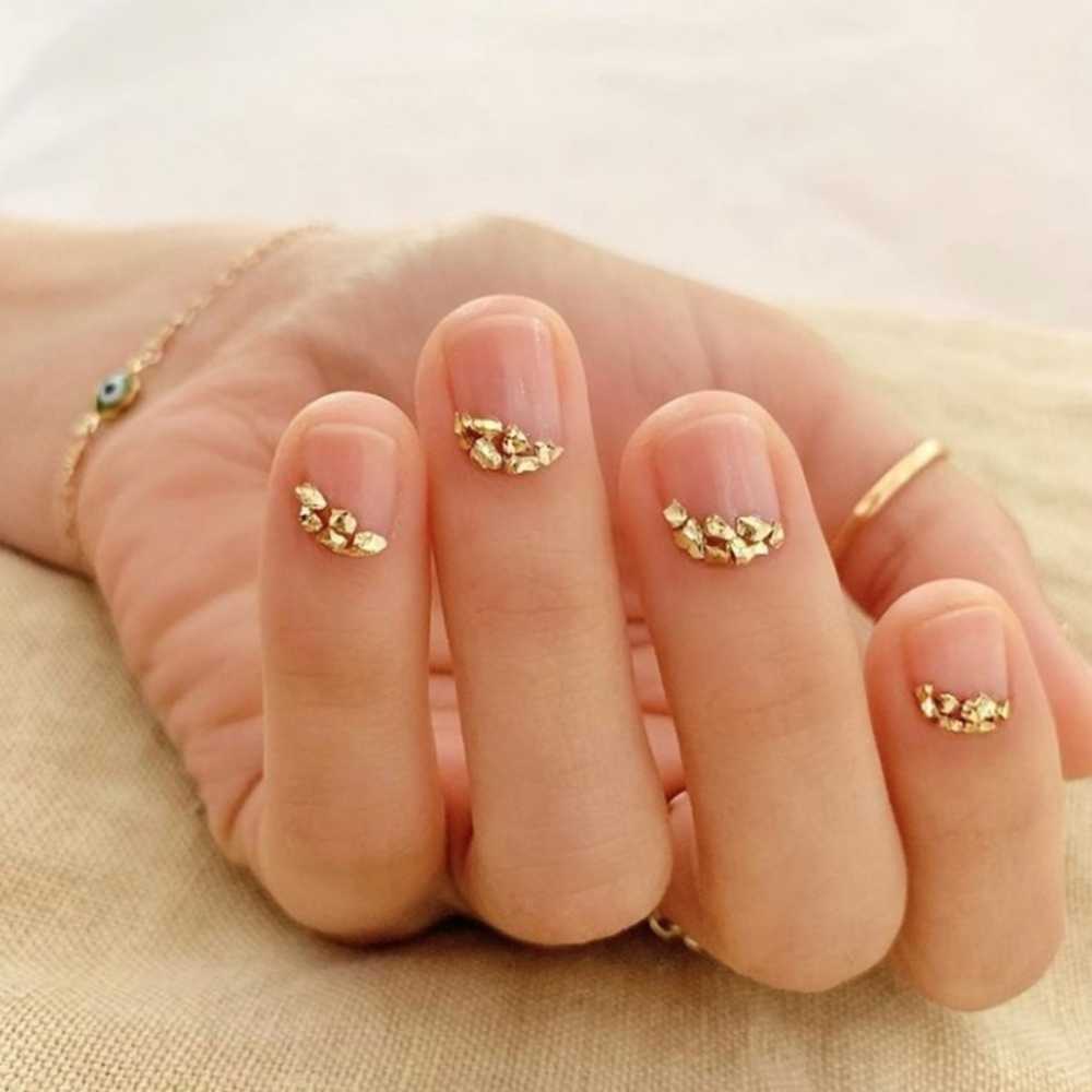 Diseño de uñas con piedras doradas en base natural