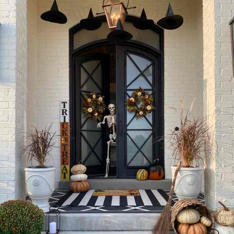 Puerta decorada con esqueleto y sombreros flotantes para Halloween