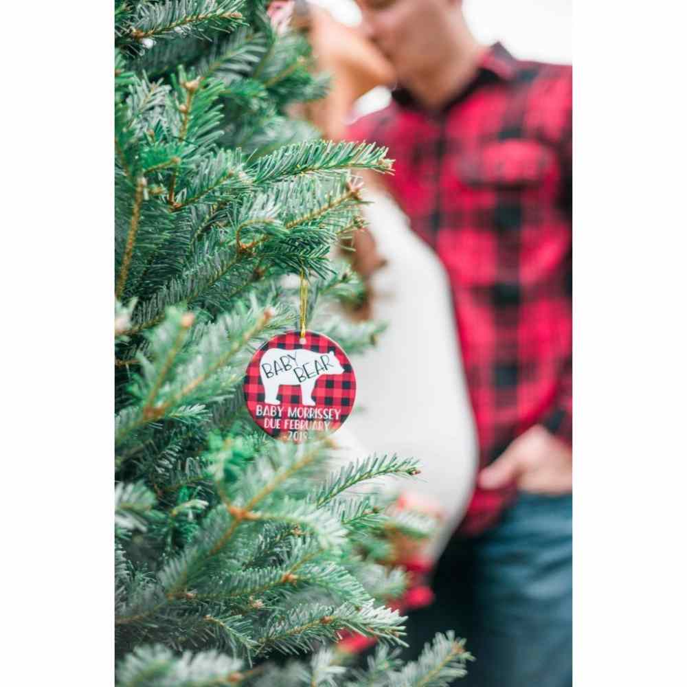 Pareja embarazada de fondo frente a árbol navideño