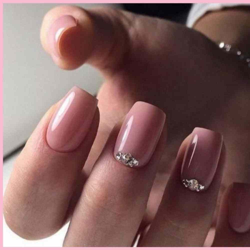 uñas rosa pastel con piedras en dedo anular y medio