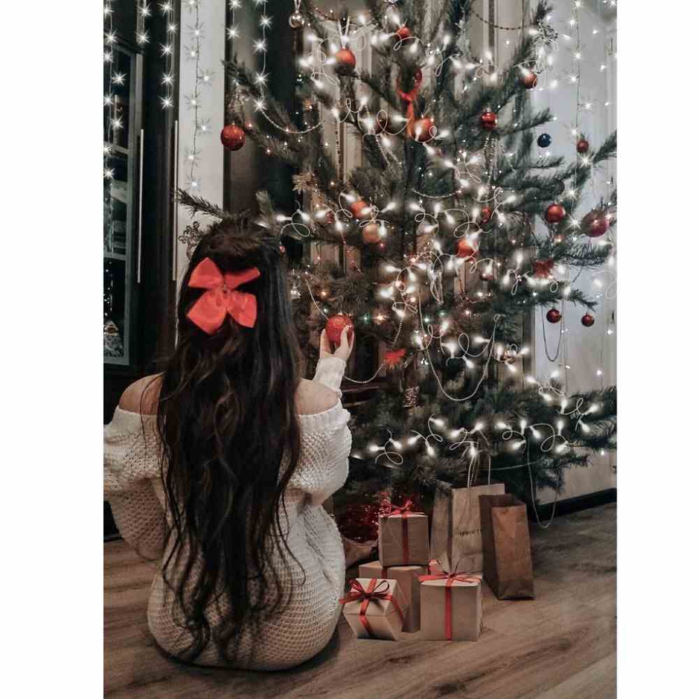 foto navideña sentada frente al árbol