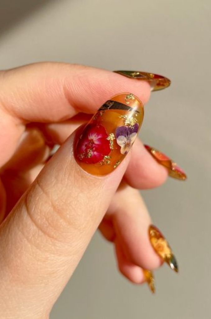 uñas color ambar con flores encapsuladas en gel o acrílico