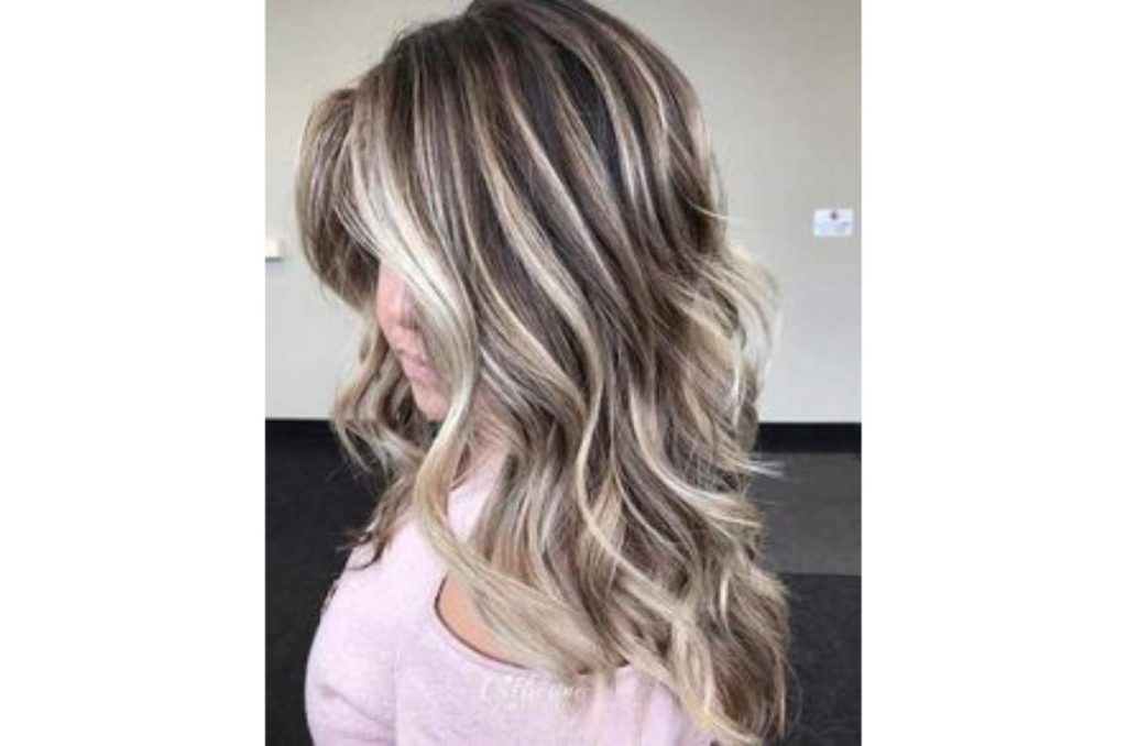 Mujer de lado mostrando su cabello negro con mechones platinados distribuidos en todo el pelo, creando luz y ayudando a disimular las canas