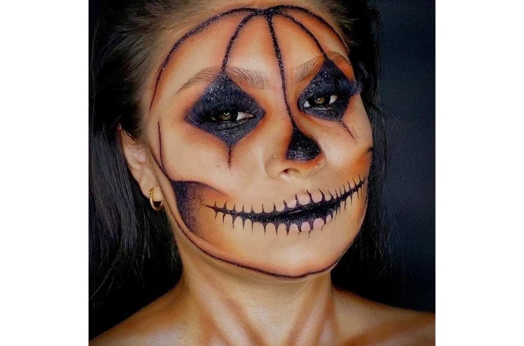 Mujer con la cara pintada como una calabaza tenebrosa