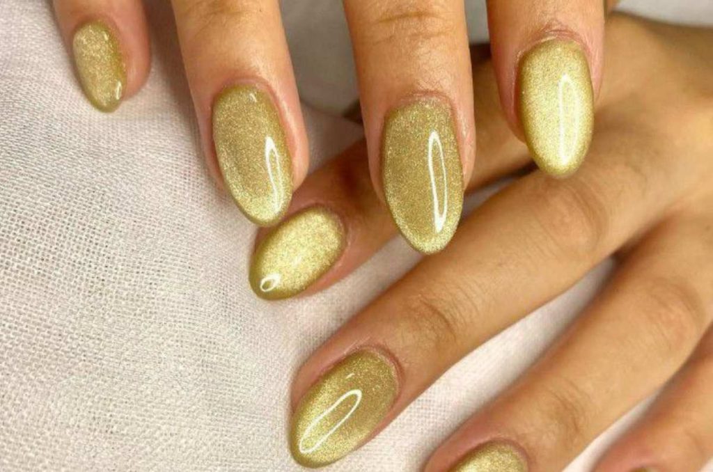 Uñas almendradas con efecto cat eye doradas