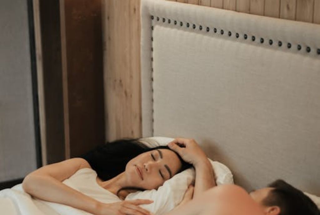 Pareja acostada y apoyada en la cabecera de la cama en habitación de motel, mostrando cercanía y complicidad