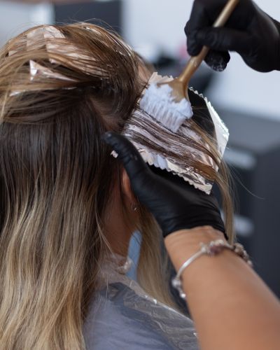 Mujer se tiñe el cabello en estética 
