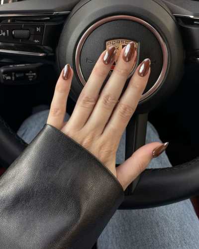 Uñas pintadas en tono café con un sutil efecto cat eye brillante