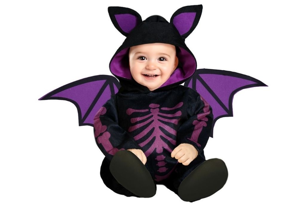 Bebé disfrazado de murciélago negro con morado, sentado sobre fondo blanco. Halloween para tu bebé con disfraz adorable y oscuro