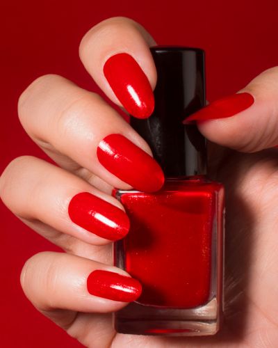 Mujer con barniz rojo en las manos con sustancias prohibidas en esmaltes y geles de uñas