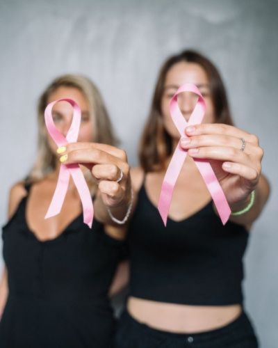 Madre e hija sosteniendo moño rosado