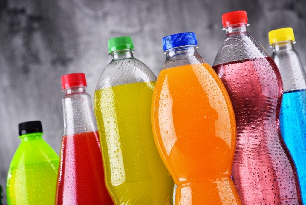 Seis refrescos de distintos tipos y colores colocados sobre una superficie, representando bebidas carbonatadas