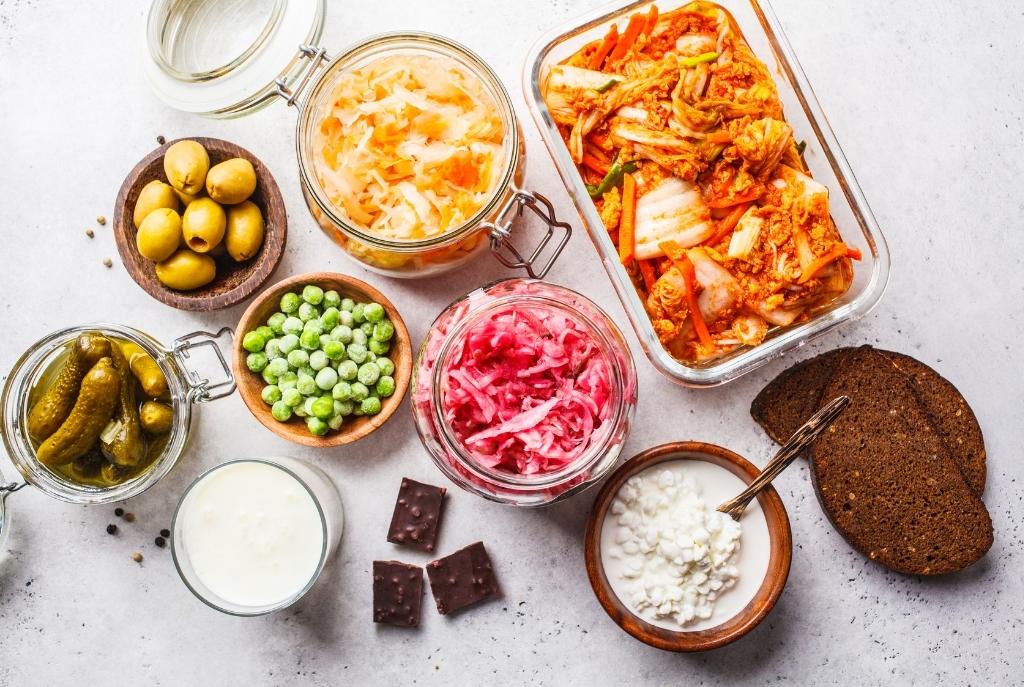 Vista superior de varios recipientes con comida saludable, incluyendo verduras y otros alimentos probióticos 