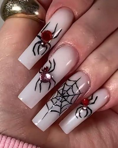 Uñas blancas con telarañas, arañas y gemas rojas