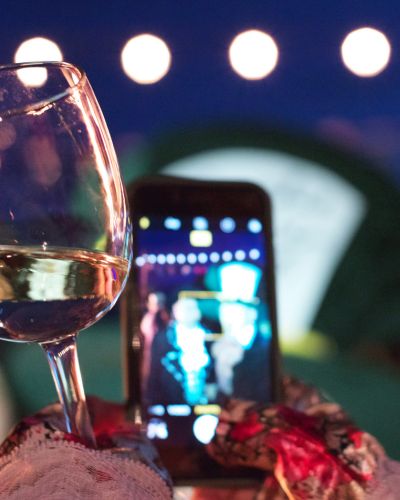 Mujer con copa en mano toma una foto con su celular