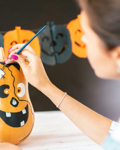 calabaza sobre una mesa, mujer pintando la calabaza