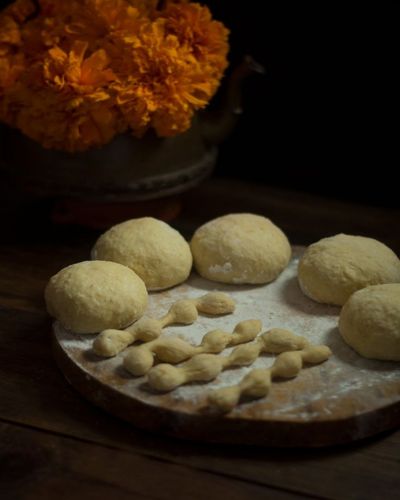 Origen de la masa de pan de muerto sin hornear, con florero de cempasúchil de fondo