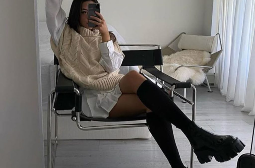 Outfit de camisa oversized, con chaleco de punto en color beige y botas negras altas